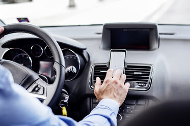 Cropped image of businessman using GPS on smart phone in car - CAVF39728