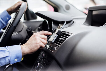 Cropped image of businessman using GPS on smart phone in car - CAVF39729