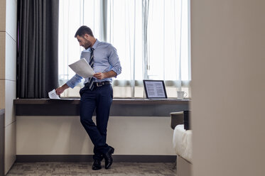 Businessman reading documents in hotel room - CAVF39732