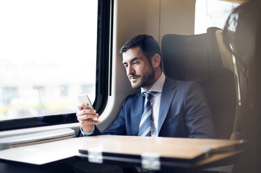 Businessman using smart phone while traveling in train - CAVF39752