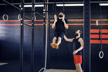 Shirtless father teaching boy to climb rope during training stock photo