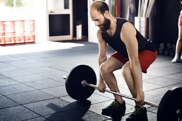 Männlicher Sportler hebt eine Langhantel im Fitnessstudio - CAVF39776