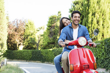 Happy couple enjoying motor scooter ride at park - CAVF39810