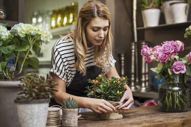 Florist arranging flowers at table in shop - CAVF39853