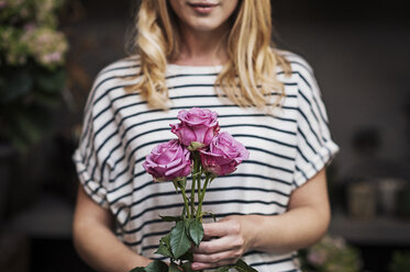 Mittelteil einer Frau mit rosa Rosen in einem Blumenladen - CAVF39857