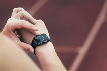 Hochformatige Ansicht eines Sportlers beim Einstellen der Smartwatch - CAVF39869