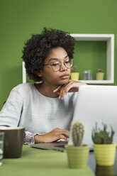 Serious woman using laptop computer having coffee at office - CAVF39876