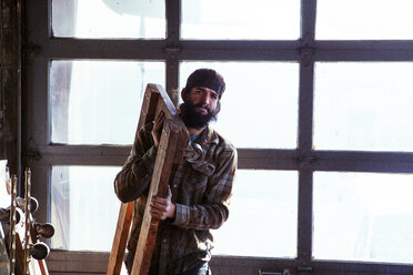 Porträt eines Arbeiters, der in einer Werkstatt Holzgeräte trägt - CAVF39908