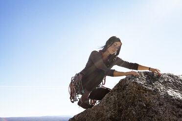 Woman rock climbing against sky on sunny day - CAVF39917