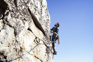 Low angle view of man rock climbing against clear sky - CAVF39922