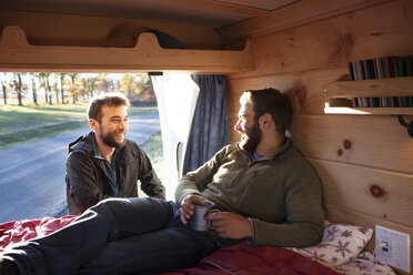 Man talking to friend relaxing in camper van - CAVF39931