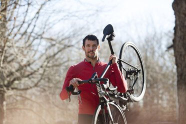 Porträt eines Sportlers mit Fahrrad im Wald - CAVF39950