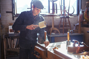 Carpenter using chisel and mallet at workshop - CAVF39971