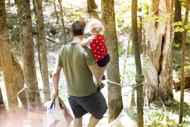 Hoher Blickwinkel des Vaters, der seine Tochter und seine Taschen beim Spaziergang im Wald trägt - CAVF40004