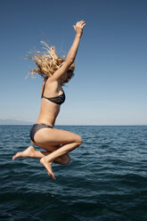 Sensuous woman in bikini diving in sea against clear blue sky - CAVF40014