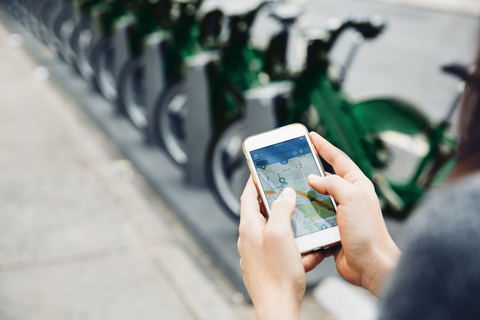 Hohe Winkel Ansicht der Frau mit Smartphone von Fahrradträger auf der Straße, lizenzfreies Stockfoto