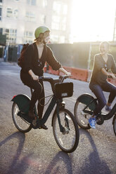 Happy friends riding bicycle on city street - CAVF40033