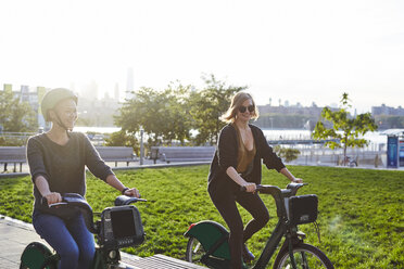 Glückliche Freunde fahren Fahrrad im Park gegen den klaren Himmel - CAVF40036