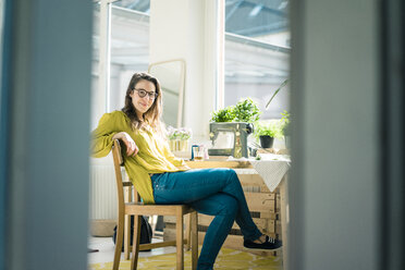 Porträt einer Modedesignerin, die in ihrem Atelier am Schreibtisch sitzt - MOEF01008