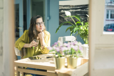 Porträt einer lächelnden Modedesignerin, die in ihrem Atelier am Schreibtisch sitzt - MOEF01029