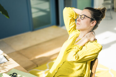 Junge Modedesignerin entspannt sich am Schreibtisch in ihrem Atelier - MOEF01030