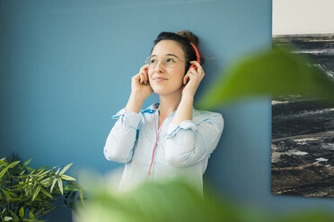 Portrait of smiling woman listening music with headphones - MOEF01035