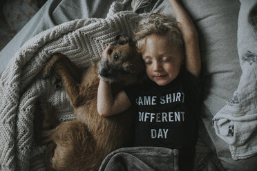 High angle view of boy sleeping with dog on bed at home - CAVF40132