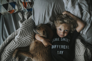 Porträt eines Jungen mit Hund auf dem Bett liegend - CAVF40133