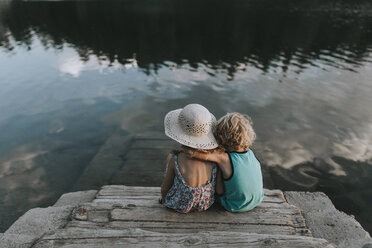 Rear view of siblings sitting on jetty steps by lake - CAVF40136