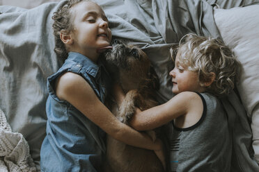 High angle view of siblings lying on bed with dog at home - CAVF40140