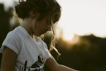 Seitenansicht eines Mädchens, das bei Sonnenuntergang vor einem klaren Himmel steht - CAVF40153