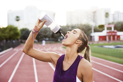 Female athlete drinking water on race tracks stock photo