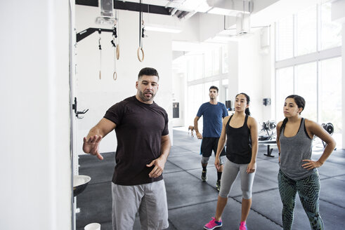 Ausbilder erklärt Athleten im Crossfit-Fitnessstudio - CAVF40236
