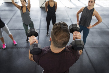 Ausbilder erklärt Athleten das Heben von Hanteln im Crossfit-Fitnessstudio - CAVF40239