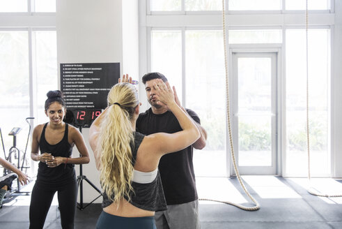 Mann gibt einer Sportlerin im Crossfit-Fitnessstudio ein High-Five - CAVF40246