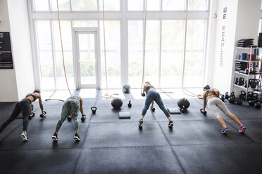 High angle view of athletes doing push-ups using dumbbells in crossfit gym - CAVF40253