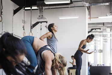 Weibliche Athleten bei einer Burpee-Übung im Crossfit-Fitnessstudio - CAVF40259