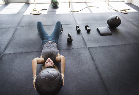 Konzentrierter Sportler beim Training mit einem Medizinball im Crossfit-Fitnessstudio - CAVF40266