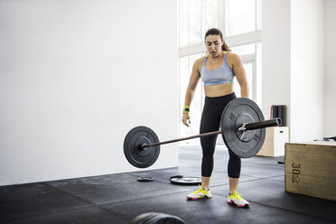 Weibliche Athletin wirft Langhantel im Crossfit-Fitnessstudio - CAVF40270