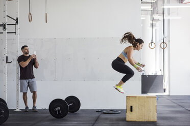 Ausbilder fotografiert Sportler beim Training auf der Jump Box im Crossfit-Fitnessstudio - CAVF40271