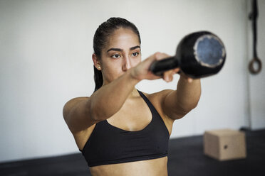 Weibliche Athletin beim Training mit der Kettlebell im Crossfit-Fitnessstudio - CAVF40272