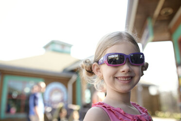 Glückliches Mädchen mit Sonnenbrille, das im Freien steht - CAVF40303