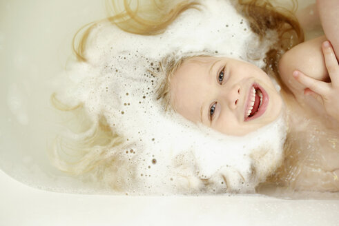 Draufsicht auf ein fröhliches Mädchen beim Baden in der Badewanne - CAVF40305