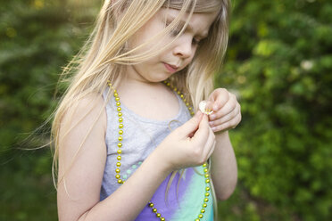 Girl holding flower while standing at backyard - CAVF40309