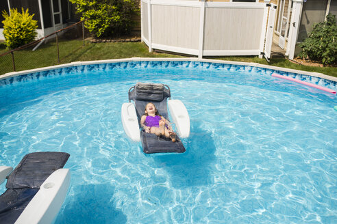 Glückliches Mädchen entspannt sich auf einem aufblasbaren Floß im Schwimmbad - CAVF40312