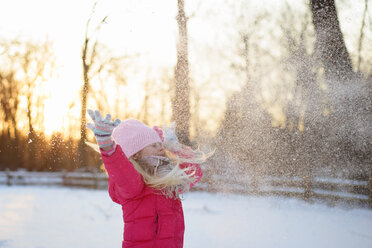 Girl in warm clothing throwing snow while standing against sky - CAVF40314