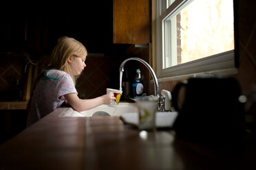 Mädchen füllt Tasse mit Wasser in Küche - CAVF40317