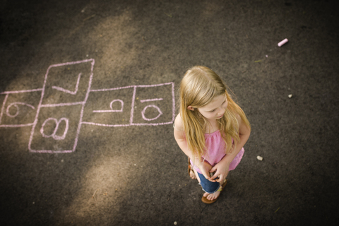 Hohe Winkel Ansicht des Mädchens stehend durch hopscotch Spiel, lizenzfreies Stockfoto