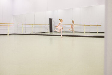 Glückliche Balletttänzerin tanzt vor einem Spiegel im Tanzstudio - CAVF40322