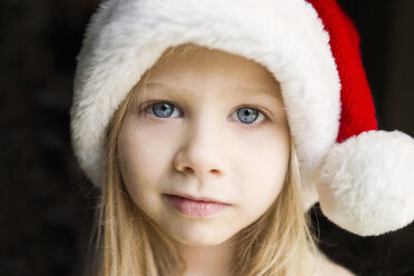 Porträt eines süßen Mädchens mit Weihnachtsmannmütze vor schwarzem Hintergrund - CAVF40337